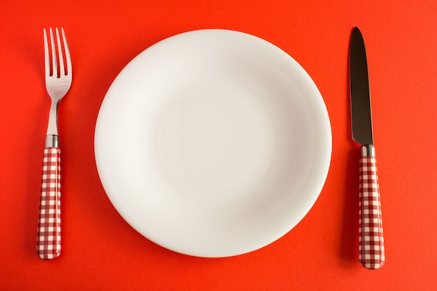 Plato blanco con cuchillo y tenedor sobre la mesa