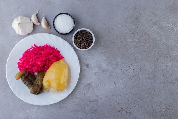 Plato blanco de diversas verduras en escabeche en la mesa de piedra.