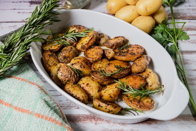 Plato blanco ovalado con deliciosas patatas asadas con hierbas frescas y naturales Vista de corte