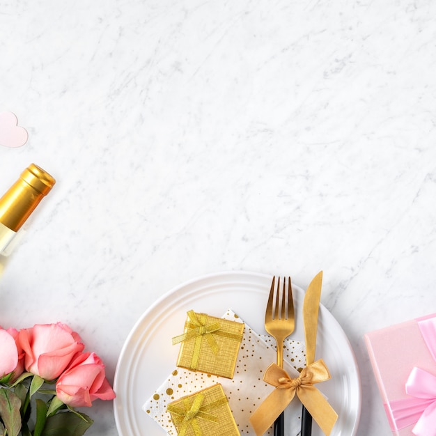 Plato blanco con regalo y flor rosa rosa sobre fondo de mesa de mármol blanco para el concepto de comida de citas especiales de San Valentín.