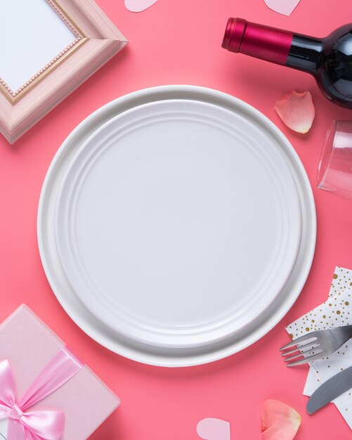 Plato blanco vacío con regalo y pétalos de rosa para el concepto de comida de citas especiales de San Valentín.