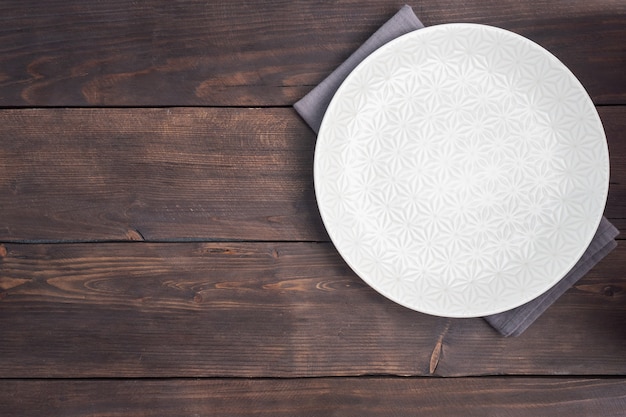 Foto plato blanco vacío sobre fondo rústico de madera. vista superior con espacio de copia.