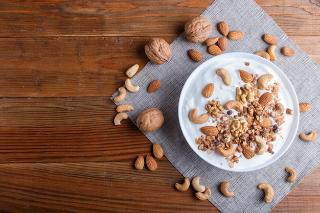 Plato blanco con yogurt griego, granola, almendra, anacardo, nueces