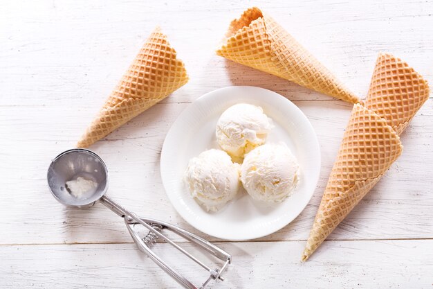 Plato de bolas de helado y conos de galleta en la mesa de madera, vista superior