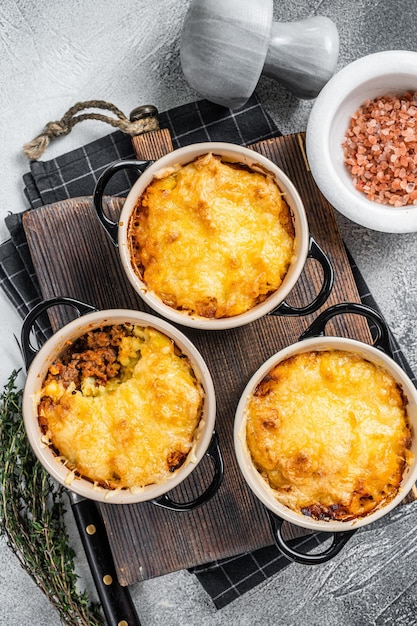 Plato británico Shepherd's pie con carne molida, puré de patatas y corteza de queso cheddar. Fondo blanco. Vista superior.