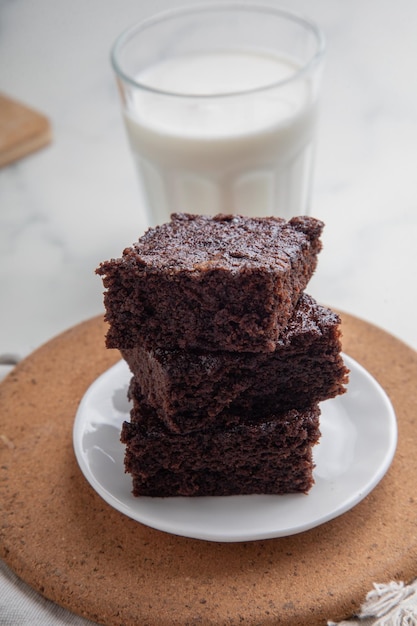 un plato de brownies con un vaso de leche en el fondo