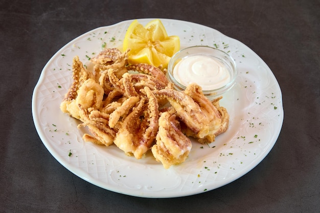 plato con calamares rebozados, limón y salsa