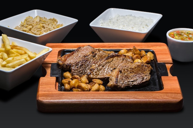 Un plato caliente con un bistec encima y dos tazones de arroz y un tazón de arroz al lado.