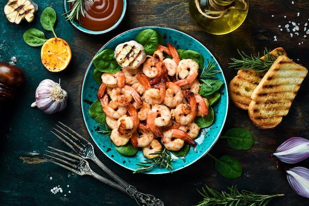 Un plato de camarones a la parrilla con hierbas, ajo y limón Sobre un fondo de piedra oscura Vista superior