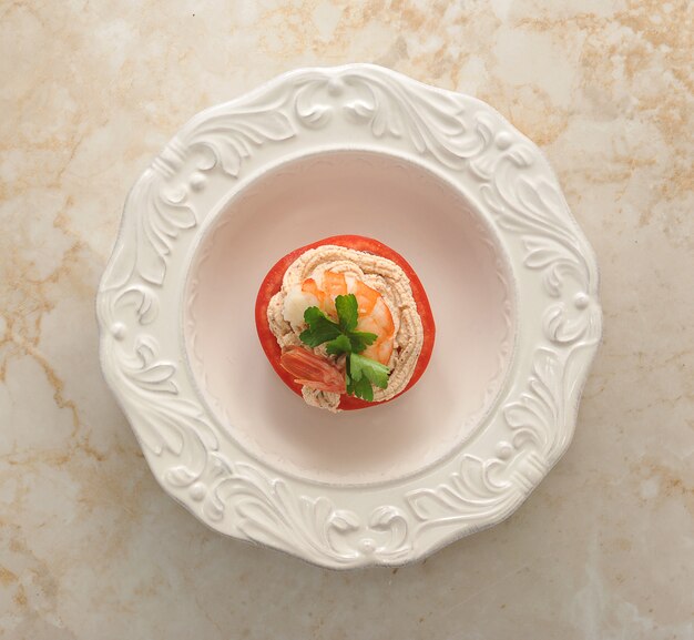 Plato de camarones y tomate sobre superficie de mármol