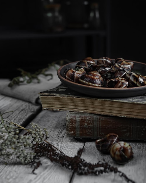 plato con caracoles franceses escargot sobre fondo de mesa de madera clara con textura antigua