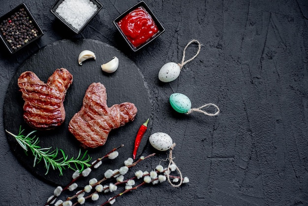 Un plato de carne con huevos y una botella de salsa roja sobre la mesa