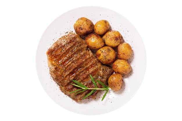 plato de carne a la parrilla con romero y patatas aisladas sobre un fondo blanco.