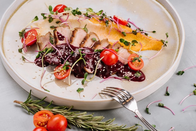 Plato de carne de pato con verduras en salsa roja y verduras