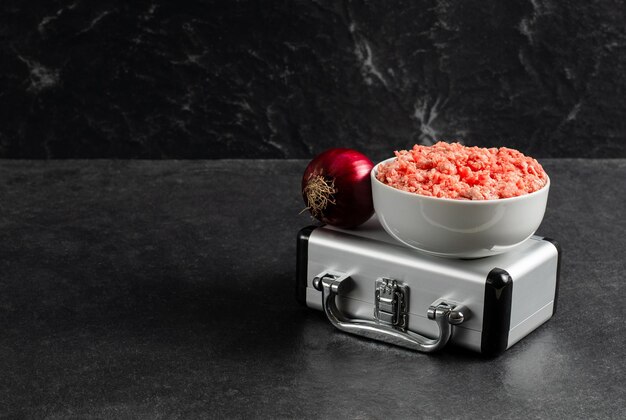 Plato con carne de res molida fresca maleta plateada cebolla roja sobre un fondo negro gris stock photox9