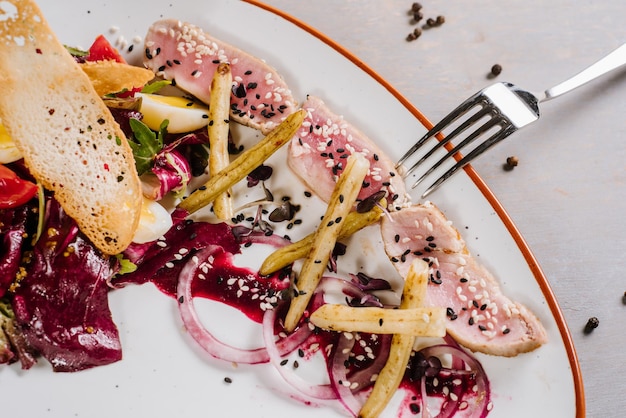 Un plato de carne con verduras, picatostes y salsa en el fondo de madera