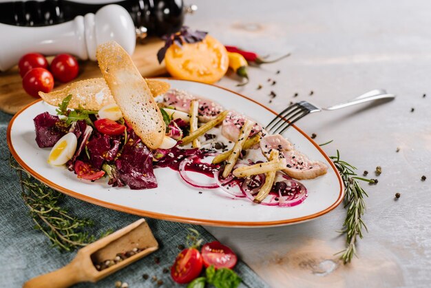 Un plato de carne con verduras, picatostes y salsa en el fondo de madera