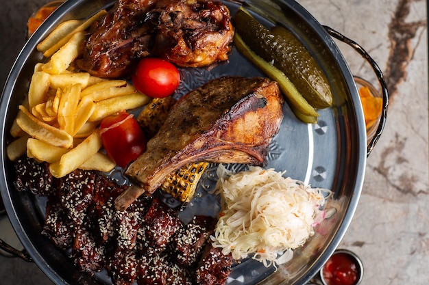 Foto plato de carnes deliciosas costillas de cerdo salchicha de pollo a la parrilla carne de res papas a la parrilla con salsa surtido de deliciosas carnes a la parrilla con vegetales y hierbas