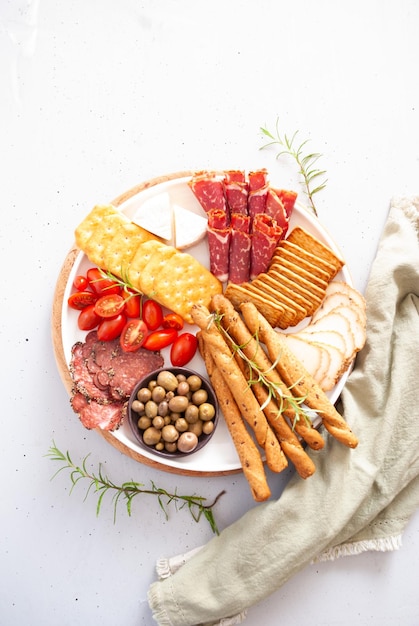 Un plato de carnes, quesos y aceitunas con una aceituna verde.