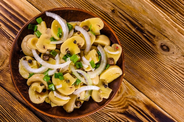 Plato de cerámica con champiñones enlatados sobre mesa de madera Vista superior