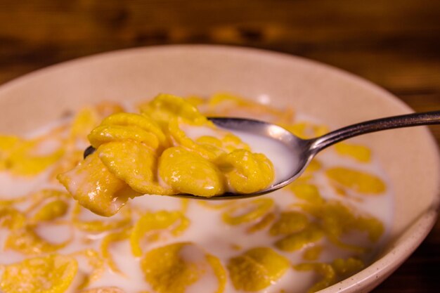 Plato de cerámica con copos de maíz y leche sobre una mesa de madera Alimentación saludable