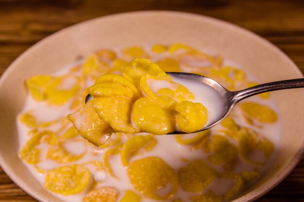 Plato de cerámica con copos de maíz y leche sobre una mesa de madera Alimentación saludable