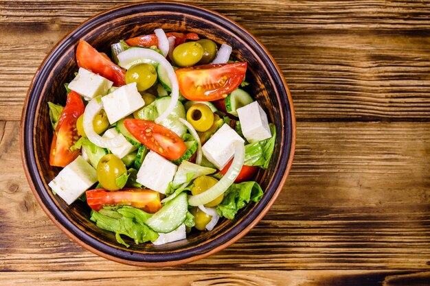 Plato de cerámica con ensalada griega en la mesa de madera Vista superior