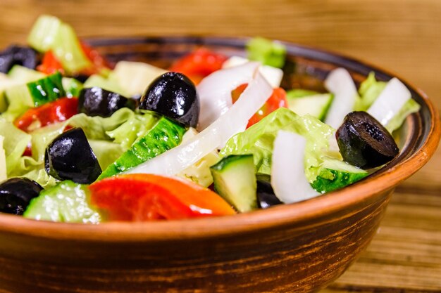 Foto plato de cerámica con ensalada griega sobre mesa de madera rústica