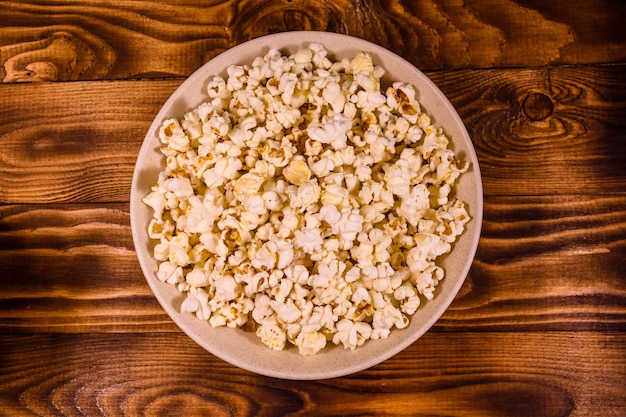 Plato de cerámica con palomitas de maíz en la mesa de madera Vista superior