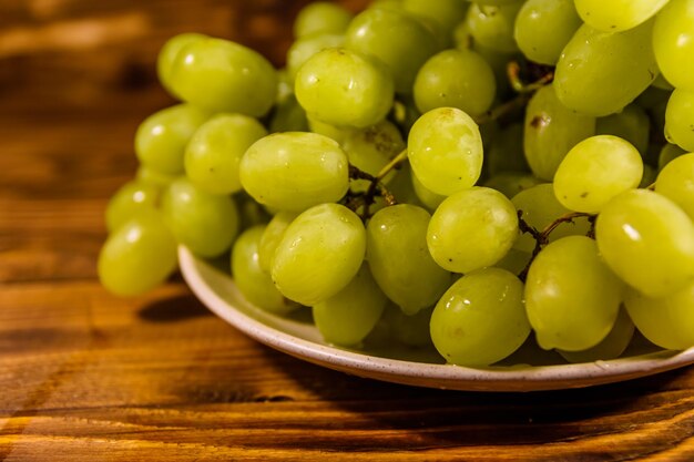 Foto plato de cerámica con uvas verdes en una mesa de madera