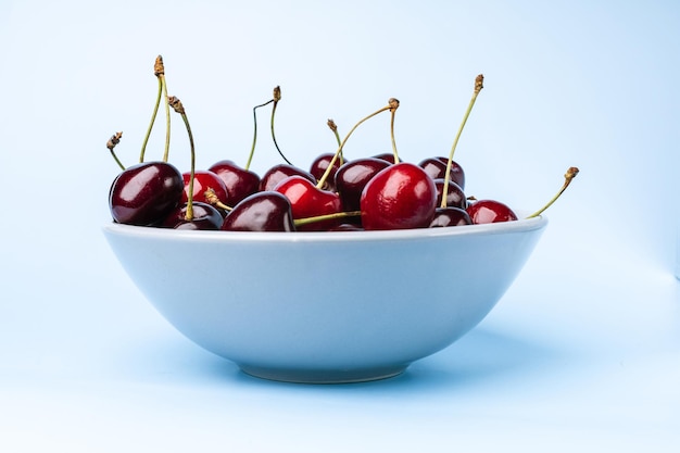 Foto un plato de cerezas sobre un fondo azul.