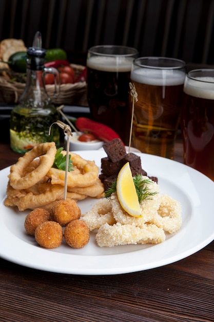 Plato con cerveza bocadillos picatostes fritos calamares cebollas y salsas