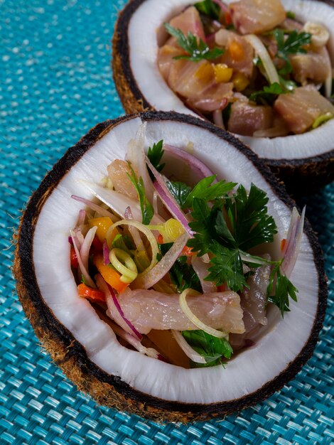 Plato de ceviche - aperitivo de pescado fresco marinado en cítricos con frutas tropicales servido en Coconut Bowls.