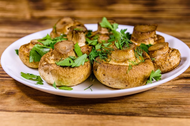 Plato con champiñones al horno, eneldo y perejil sobre una mesa de madera