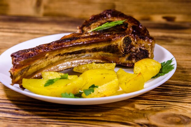 Plato con chuletón asado y patatas en mesa de madera rústica