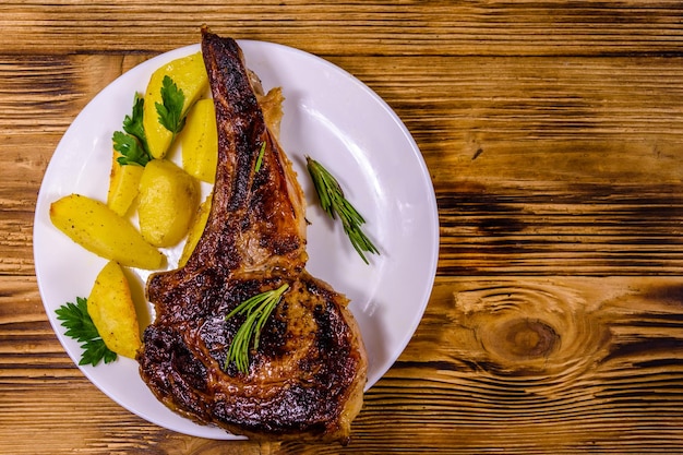 Plato con chuletón asado sobre una mesa rústica de madera. Vista superior