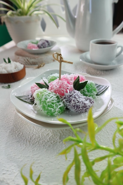 Un plato de coloridos postres tailandeses en una mesa con té y café.