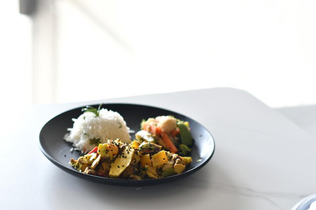 Un plato de comida con arroz blanco en una mesa