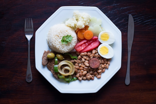 Plato de comida brasileña Frijoles, arroz, carne, huevos, ensalada.