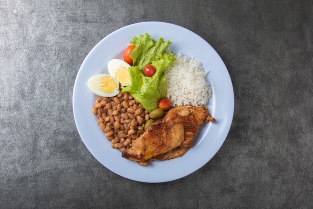 Plato de comida brasileña con frijoles de arroz y vista superior de pollo.