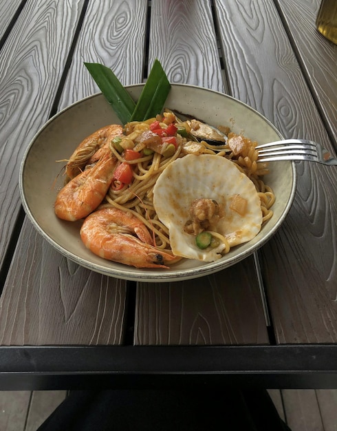 Un plato de comida con camarones y fideos y un tenedor.