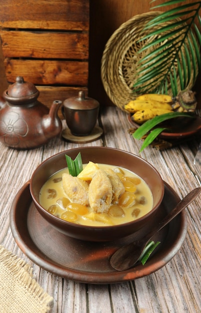 Un plato de comida con una cuchara y una olla de hojas de plátano sobre la mesa.