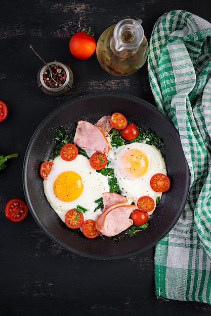 Plato con comida de dieta ceto Jamón de huevo frito Espinaca y tomates Desayuno ceto paleo Vista superior espacio de copia