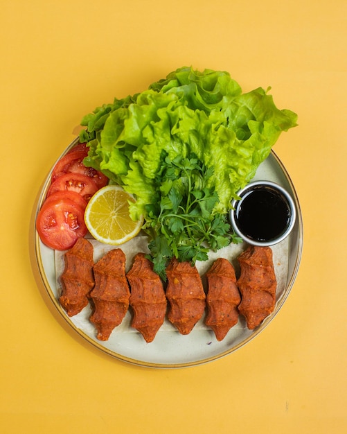 Un plato de comida con una guarnición de lechuga y salsa de tomate.