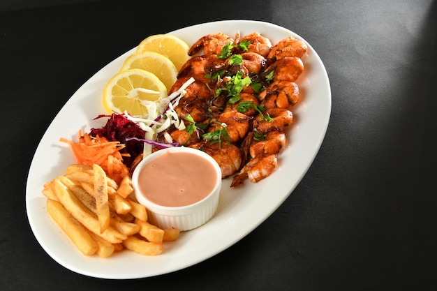 Un plato de comida con papas fritas y un tazón de salsa.