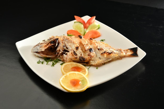 Un plato de comida con un pescado entero encima