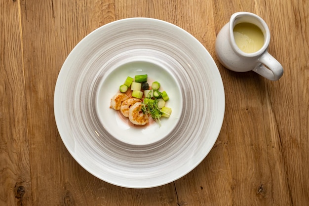 Un plato de comida con un plato de vieiras y una taza de salsa