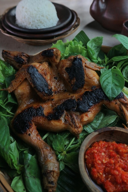 Un plato de comida con un pollo encima y un plato de salsa roja al lado.