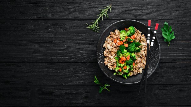 Un plato de comida saludable Avena con brócoli, zanahorias y perejil Vista superior Sobre un fondo negro Espacio de copia libre