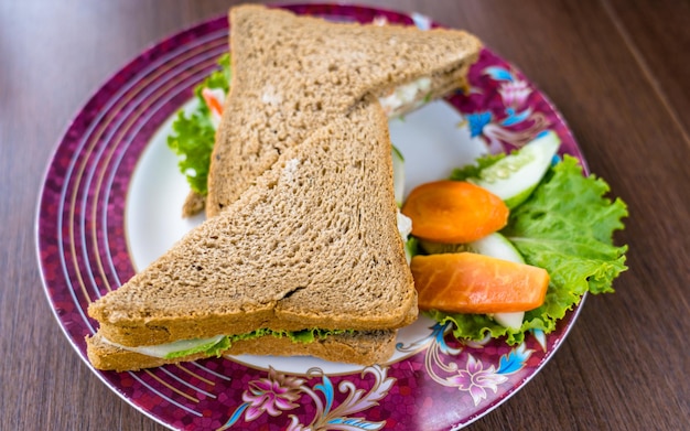 Un plato de comida con un sándwich encima.